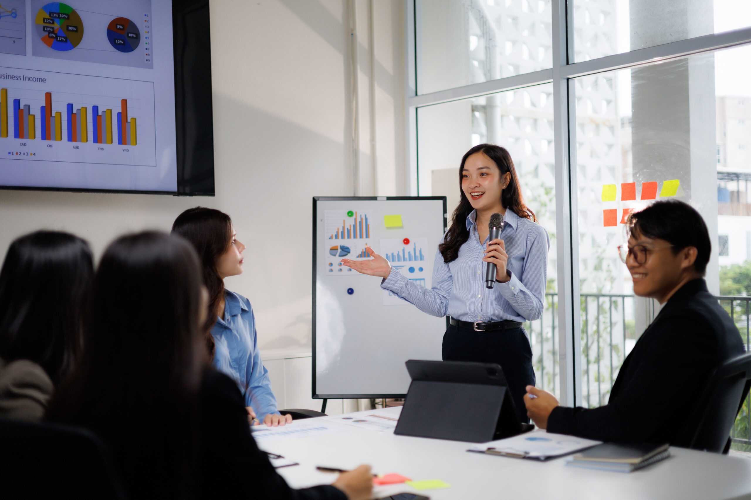 A young business professional delivering a pitch to her clients in a boardroom.