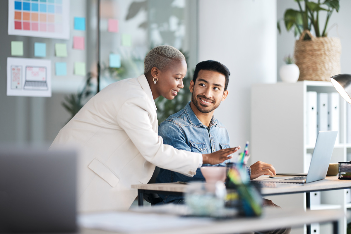 A young business professional being coached by his senior colleague in a relaxed office setting.