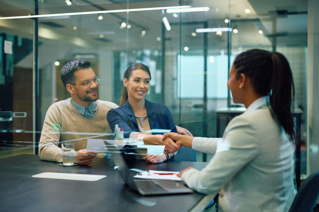 A business professional shaking hands with clients after closing a deal.