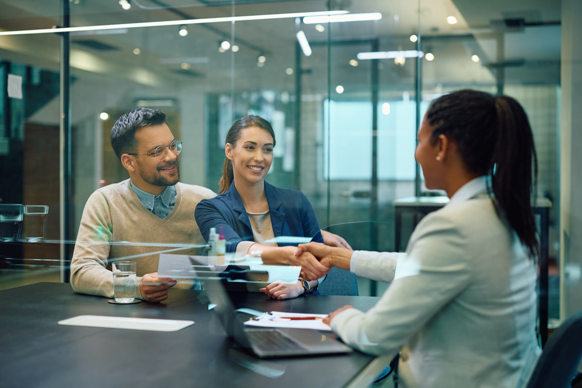 A business professional shaking hands with clients after closing a deal.
